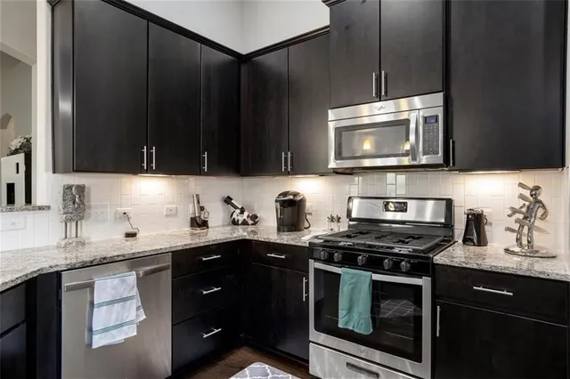 a kitchen with stainless steel appliances a stove a sink a stove a microwave cabinets and a sink