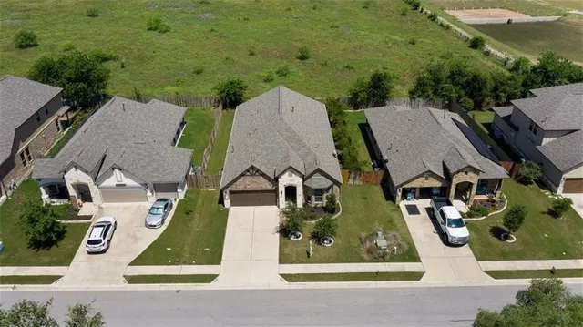 an aerial view of residential houses with outdoor space and parking