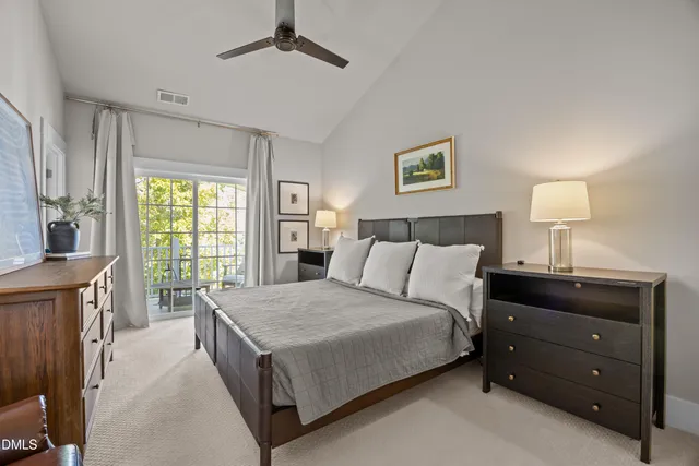 a spacious bedroom with a bed and a lamp on dresser