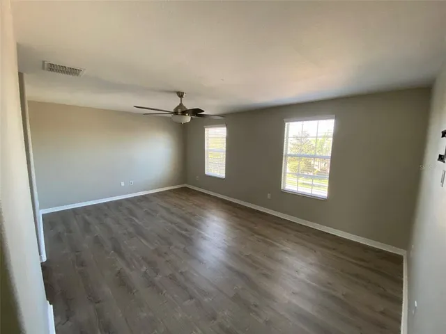an empty room with wooden floor cabinet and windows