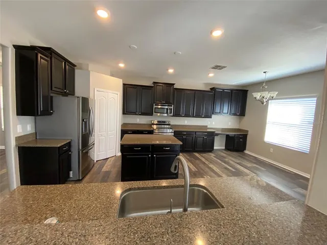 a kitchen with stainless steel appliances granite countertop a sink stove and refrigerator