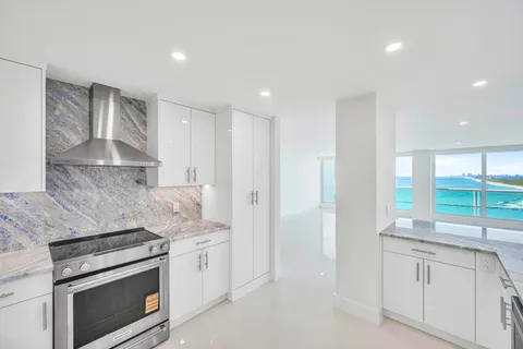 a kitchen with granite countertop white cabinets stainless steel appliances and a counter space