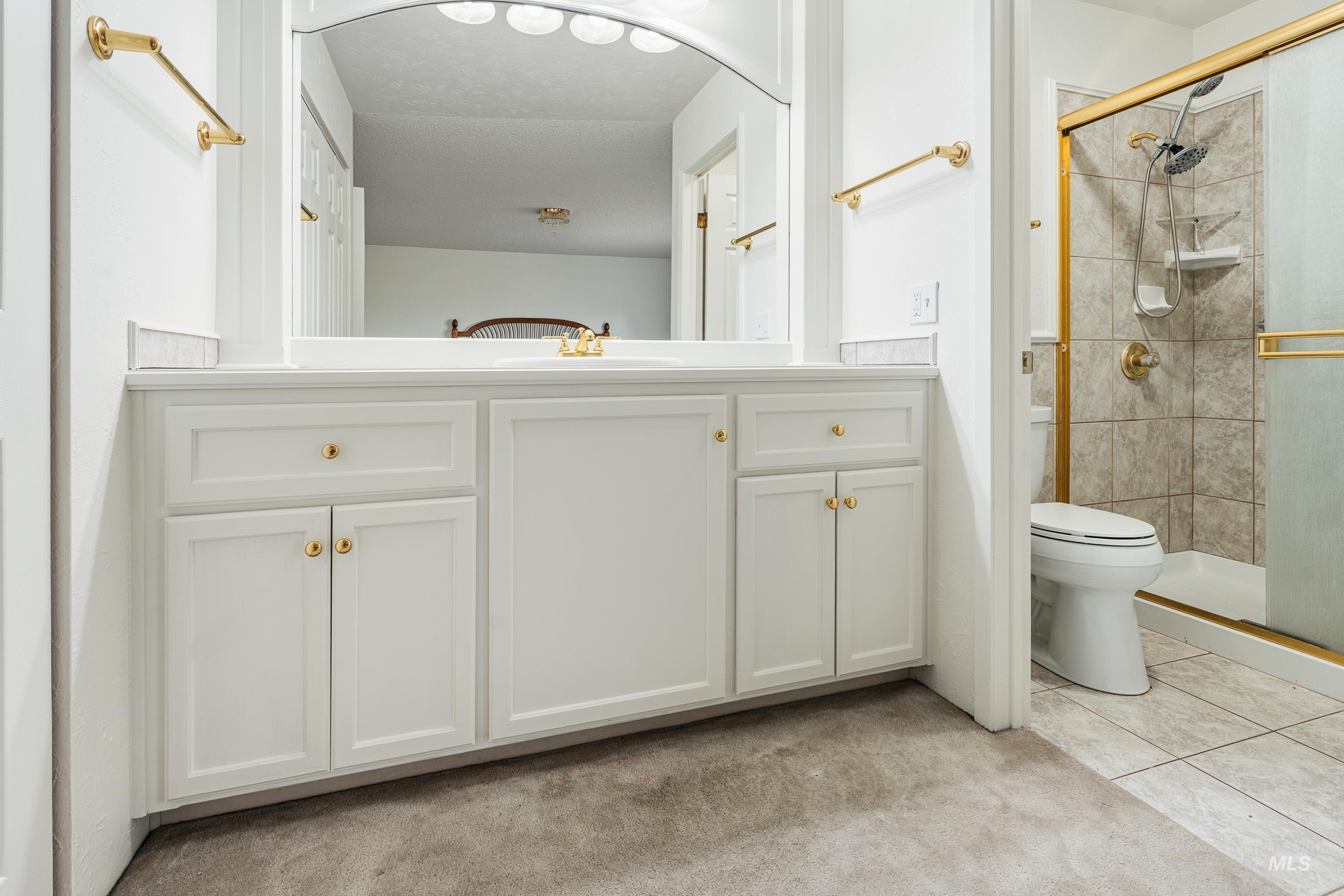 2963 Mayfair Ridge Lewiston, ID 83501 - Photo 15 of 45 White vanity with gold-tone hardware, a large mirrored surface, and a shower enclosure with a gold-tone frame and tile surround