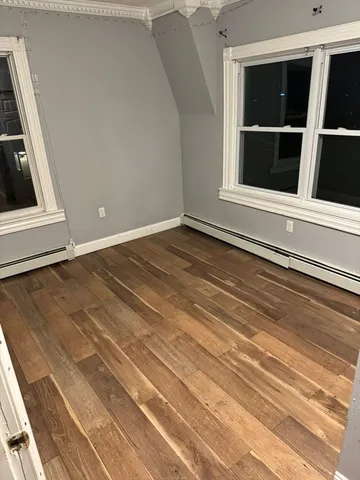a view of an empty room with wooden floor and windows