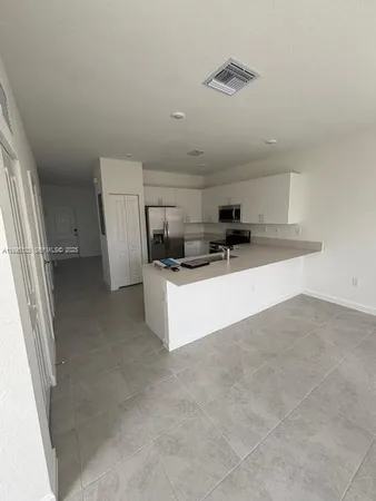 a view of a refrigerator in kitchen and an empty room