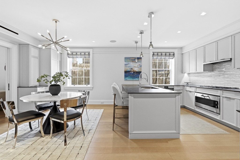 25 Beacon Street, Unit 4 Boston, MA 02108 - Photo 11 of 41 a open kitchen with stainless steel appliances kitchen island granite countertop a stove a sink a dining table and chairs with wooden floor
