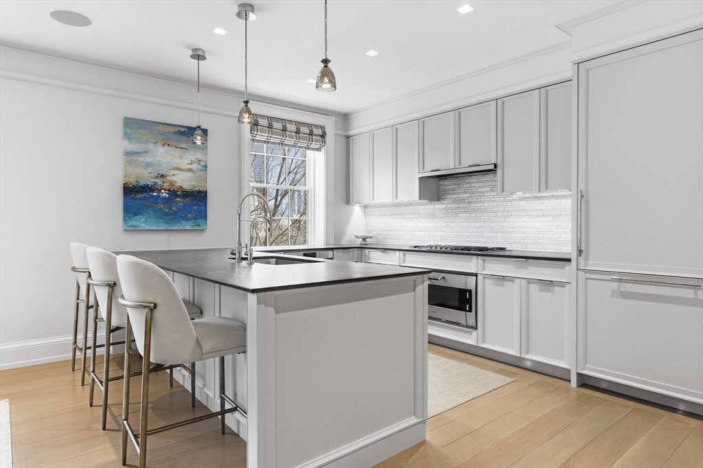 25 Beacon Street, Unit 4 Boston, MA 02108 - Photo 13 of 41 a kitchen with kitchen island granite countertop a table chairs refrigerator and microwave