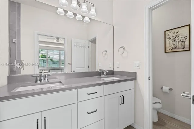 a bathroom with a granite countertop sink a mirror and a toilet