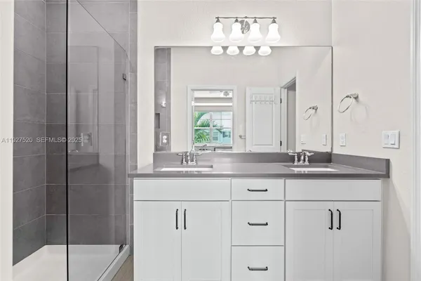 a bathroom with a granite countertop sink a mirror and a shower