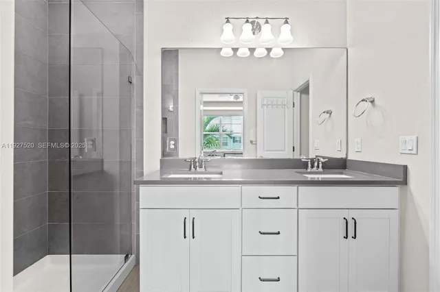 a bathroom with a granite countertop sink a mirror and a shower