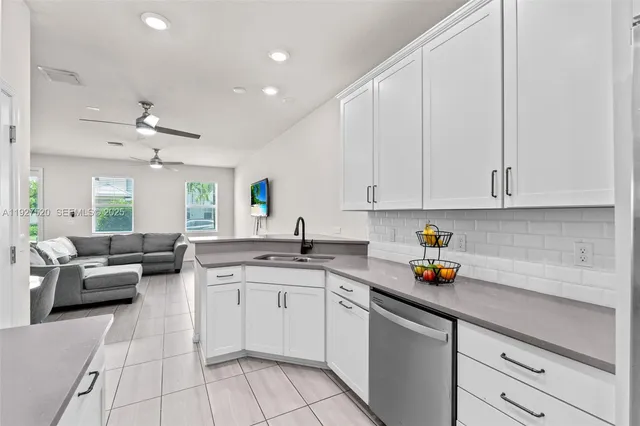 a kitchen with a sink dishwasher and white cabinets with wooden floor