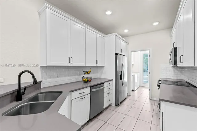 a kitchen with granite countertop a sink stainless steel appliances and cabinets
