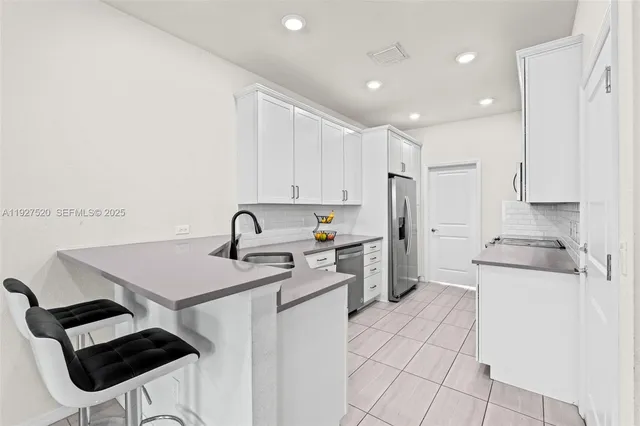a kitchen with a sink a stove a refrigerator and white cabinets