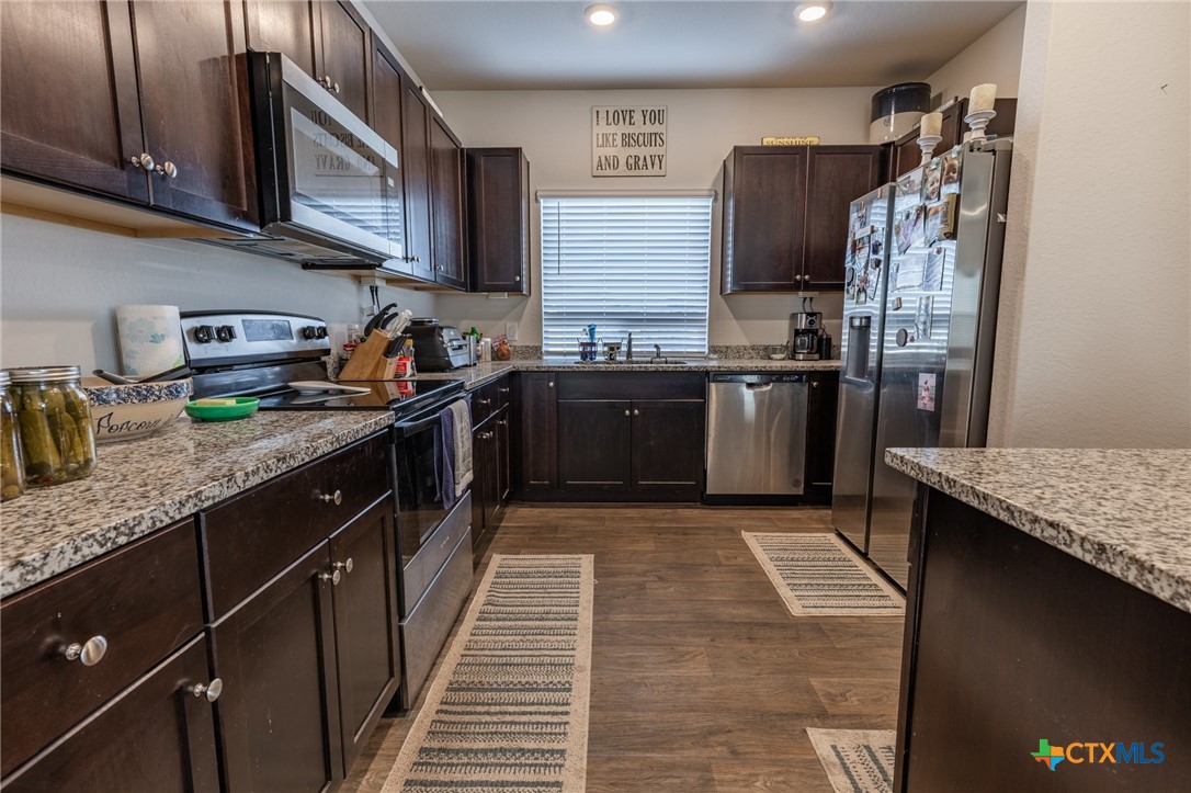 929 Indigo Way Seguin, TX 78155 - Photo 12 of 30 a kitchen with stainless steel appliances granite countertop a sink stove and refrigerator