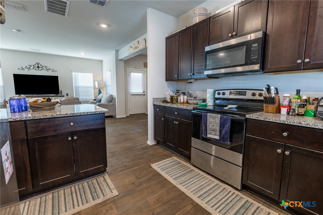 929 Indigo Way Seguin, TX 78155 - Photo 13 of 30 a kitchen with stainless steel appliances granite countertop wooden cabinets a stove top oven a sink and dishwasher