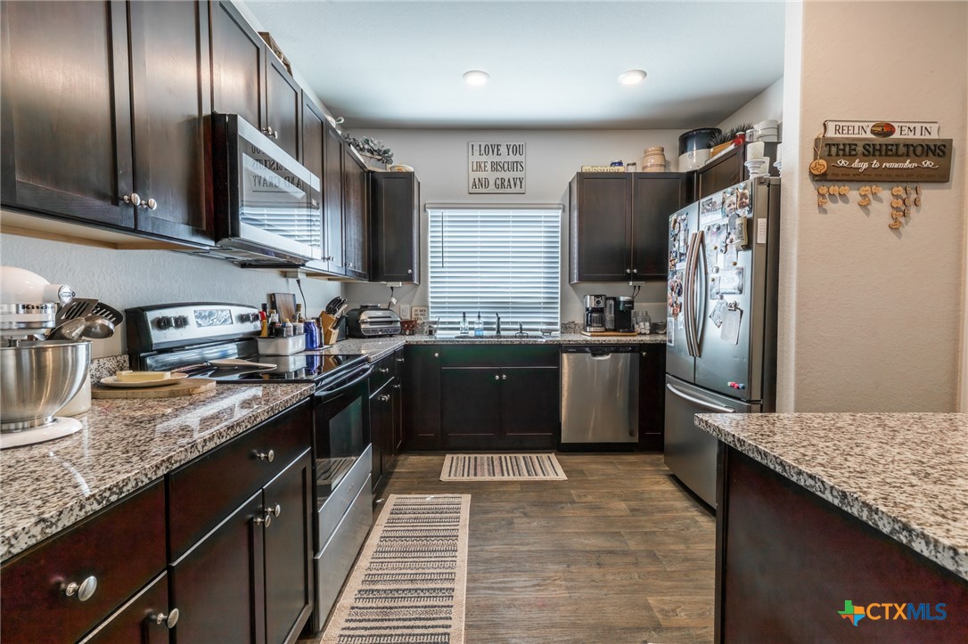 929 Indigo Way Seguin, TX 78155 - Photo 10 of 37 a kitchen with granite countertop stainless steel appliances a sink stove and refrigerator