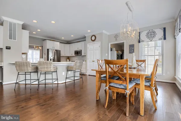 a view of a dining room and livingroom with furniture wooden floor a chandelier