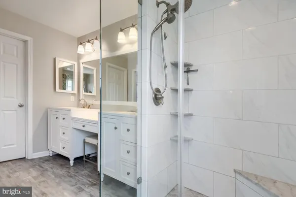 a bathroom with a double vanity sink a mirror a glass door and shower