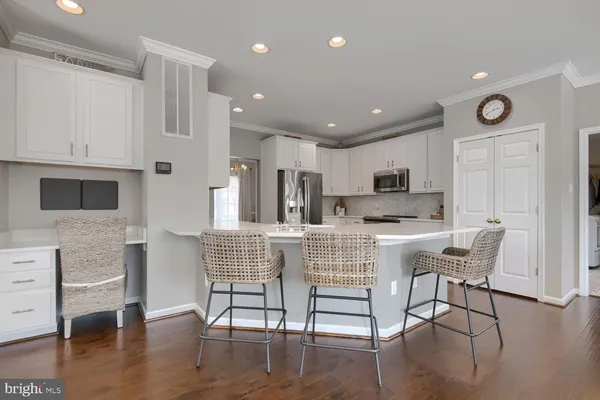 a kitchen with stainless steel appliances kitchen island granite countertop a refrigerator a stove a dining table and chairs with wooden floor
