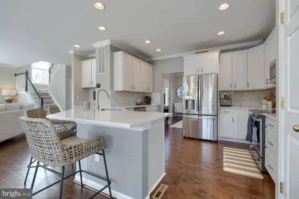 a kitchen with stainless steel appliances granite countertop a refrigerator a sink dishwasher a stove and white cabinets with wooden floor