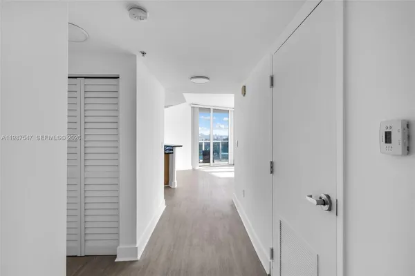 a view of a hallway with wooden floor and closet area