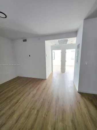 a view of an empty room and wooden floor and windows
