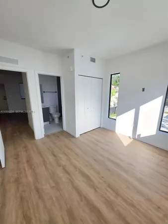 a view of empty room with window and wooden floor