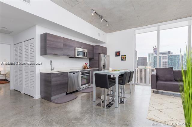 151 Southeast 1st Street, Unit 2811 Miami, FL 33131 - Photo 2 of 18 a kitchen with stainless steel appliances kitchen island granite countertop a table and chairs in it