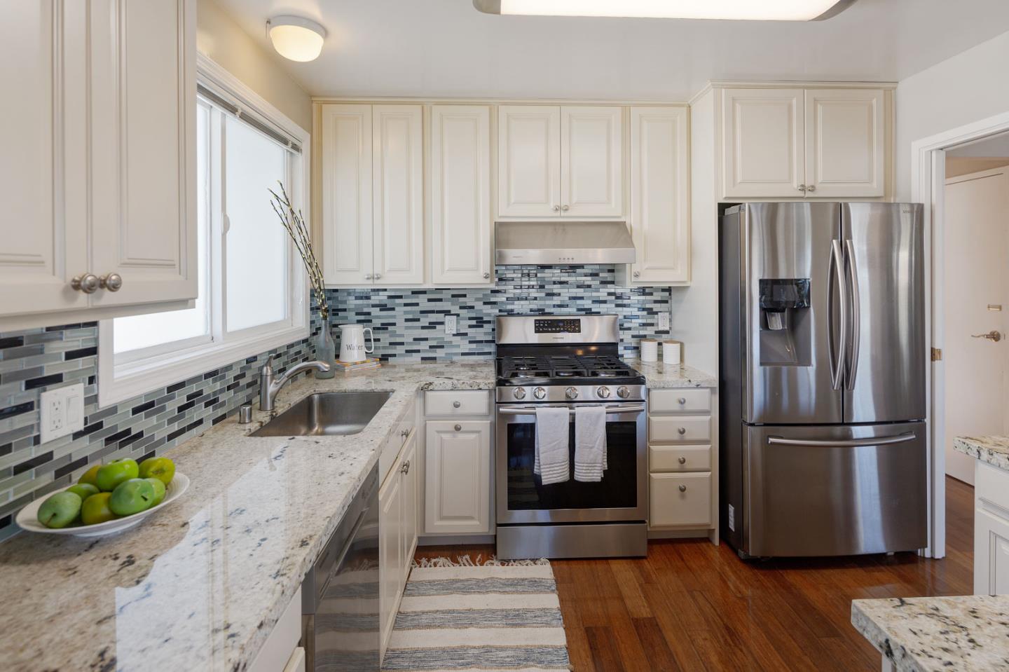 17 Moon Gate Court Pacifica, CA 94044 - Photo 14 of 36 a kitchen with stainless steel appliances granite countertop a refrigerator a stove and a wooden floors