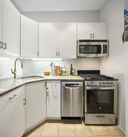 a kitchen with cabinets stainless steel appliances and sink