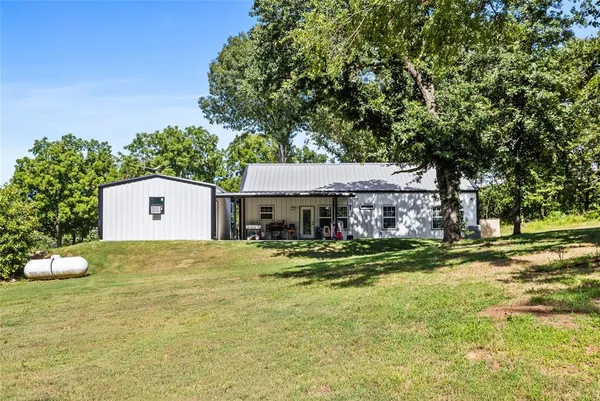 a view of a big house with a big yard and large tree