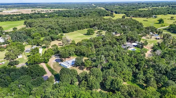 an aerial view of residential houses with outdoor space and trees