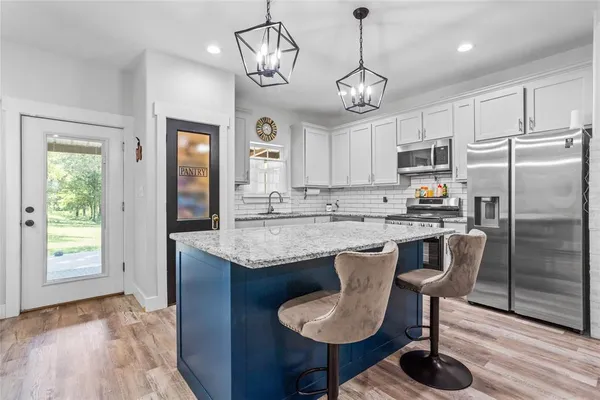 a kitchen with kitchen island granite countertop a center island a stove cabinets a dining table and chairs