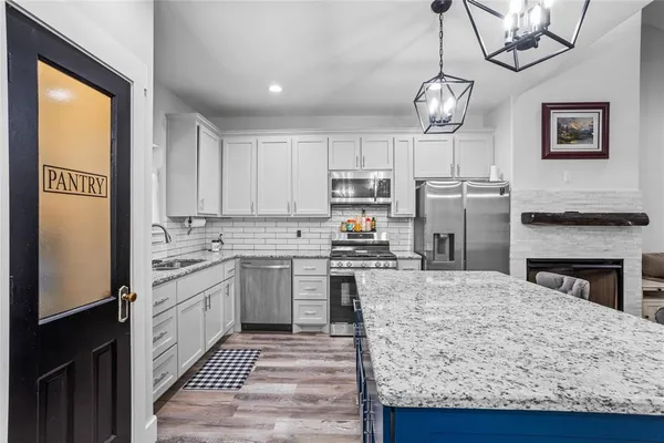 a kitchen with kitchen island granite countertop a stove top oven a sink a counter space and cabinets