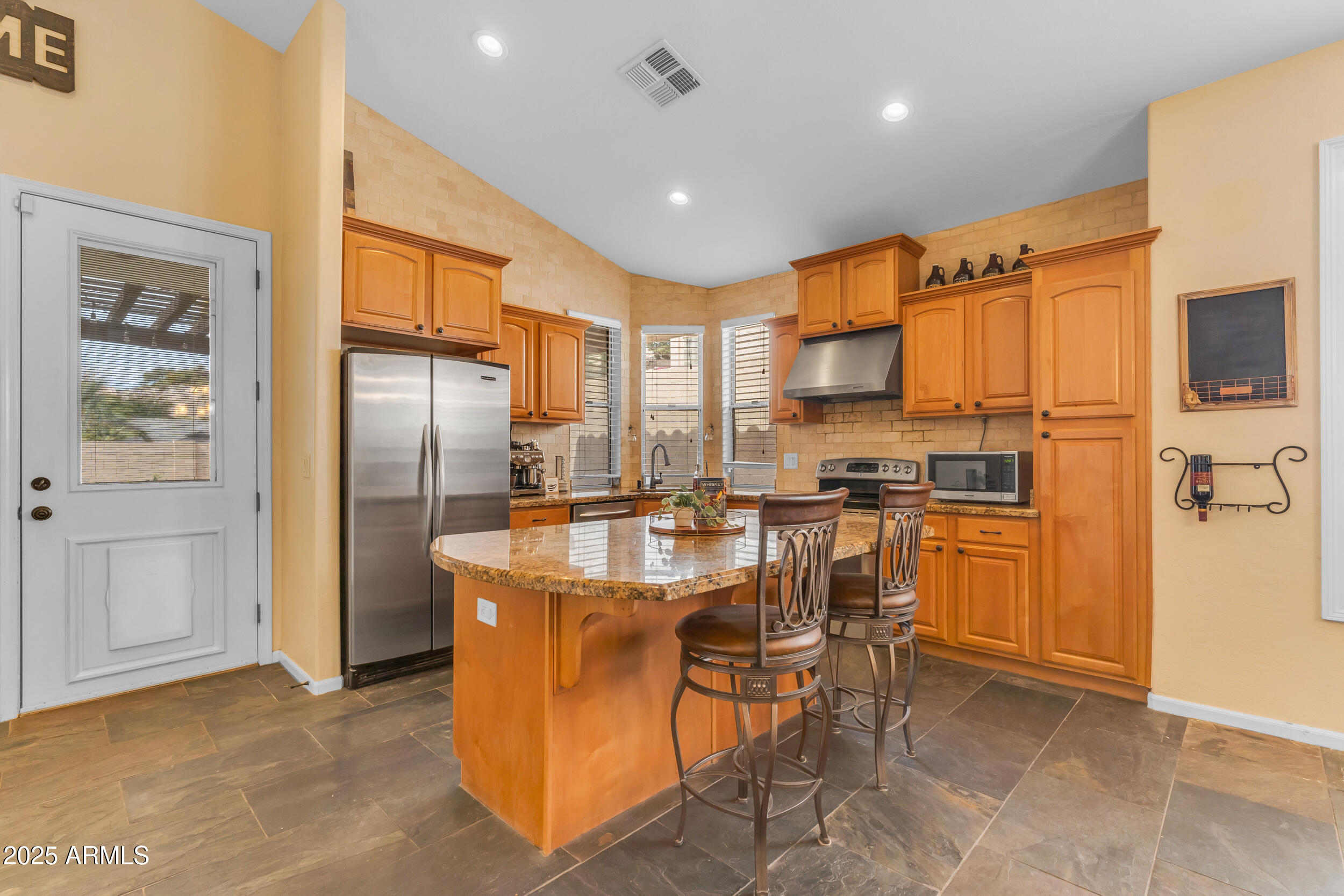 16044 South 24th Place Phoenix, AZ 85048 - Photo 12 of 42 a kitchen with stainless steel appliances granite countertop a refrigerator a stove a sink a dining table and chairs with wooden floor
