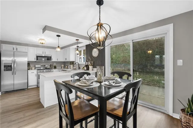 a dining room with wooden floor a chandelier a wooden table and chairs