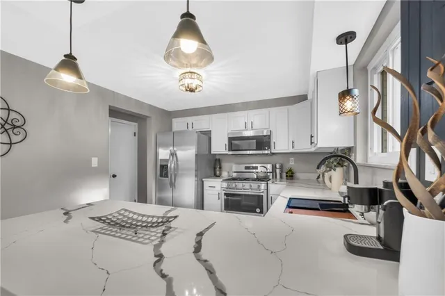 a kitchen with stainless steel appliances kitchen island granite countertop a sink stove and refrigerator