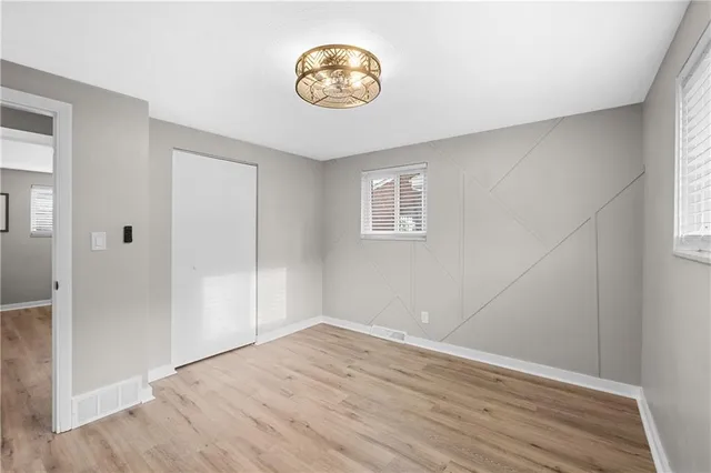 a view of empty room with wooden floor and window