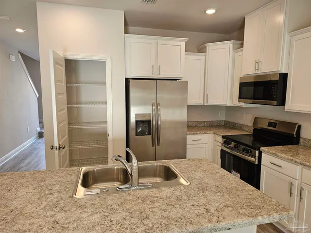 a kitchen with granite countertop a refrigerator and a sink