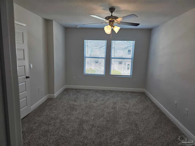 an empty room with window and ceiling fan
