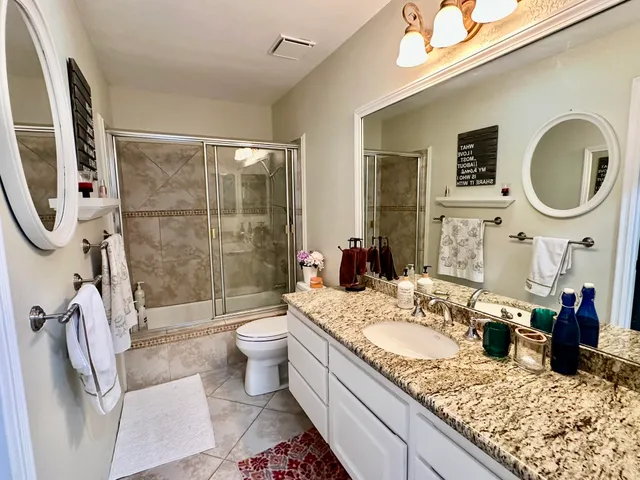a bathroom with a granite countertop sink mirror vanity and toilet