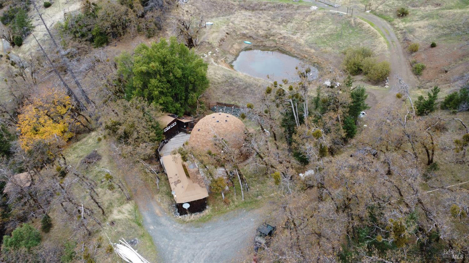 an aerial view of a house with a yard and large tree