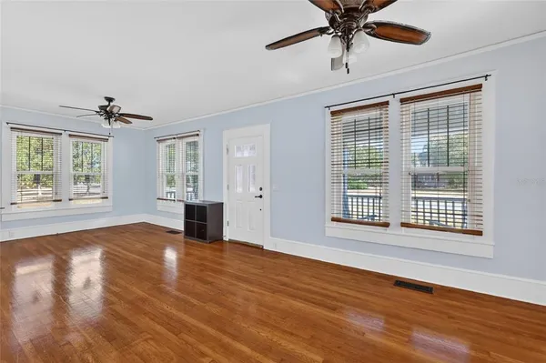 a view of an empty room with a window and wooden floor