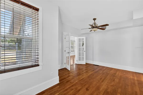 a view of empty room with wooden floor and fan