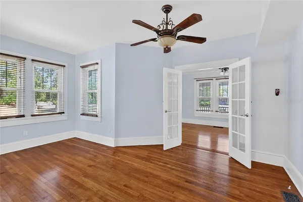 a view of empty room with wooden floor and fan