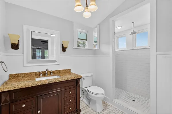 a bathroom with a granite countertop sink a toilet and a mirror