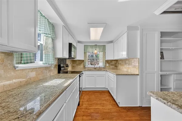 a large kitchen with a stove top oven a sink dishwasher a dining table and chairs with wooden floor