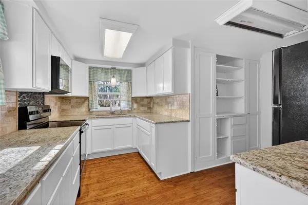 a kitchen with granite countertop kitchen island a sink stainless steel appliances and cabinets