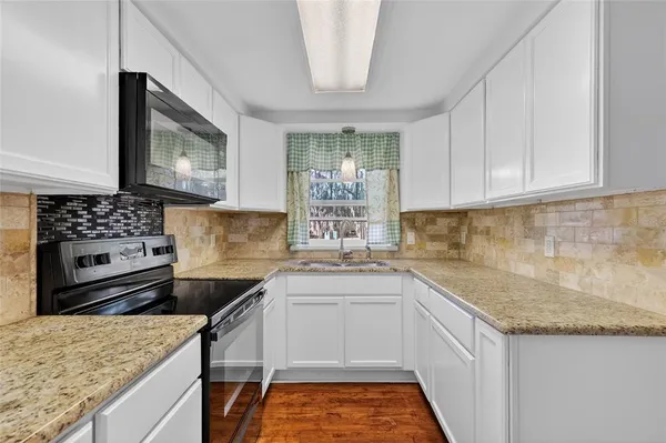 a kitchen with granite countertop a sink stove and cabinets