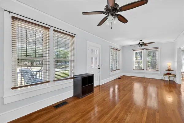 a view of empty room with wooden floor and fan